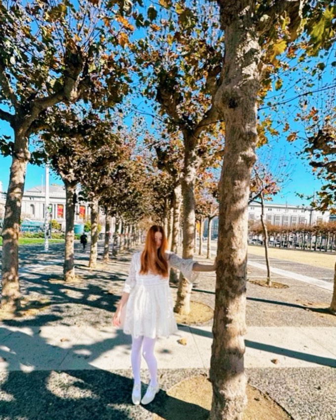 Suzanne in a white dress beneath an avenue of autumn plane trees